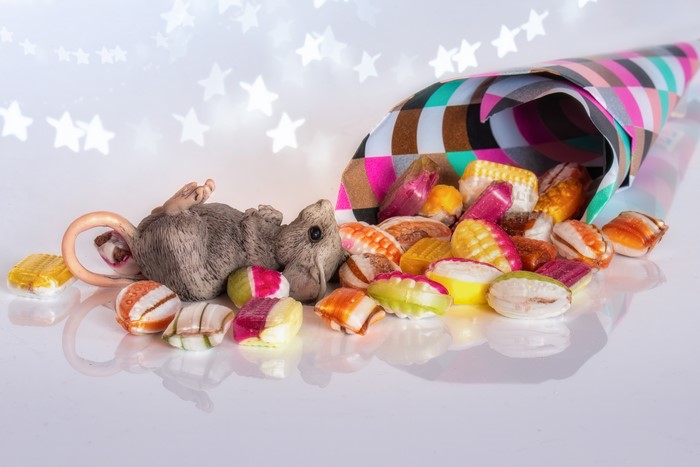 Mouse and colorful candies spilling from a cone