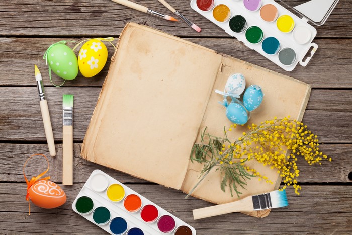 Easter eggs, paint, and brushes on wood planks