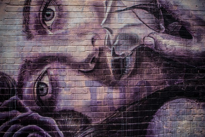 Graffiti of a face with eyes on a brick wall