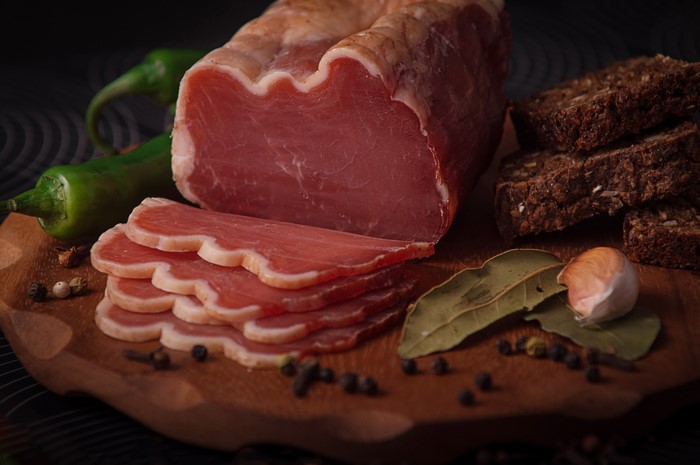 Sliced cured meat with bread, peppers, and garlic