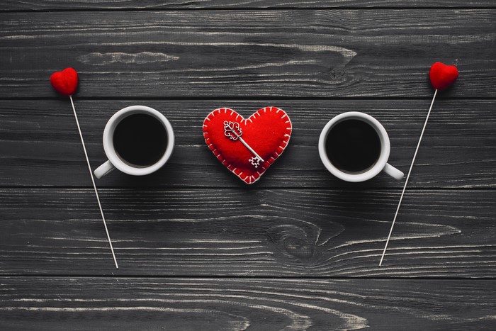 Coffee cups with hearts and key on wood planks