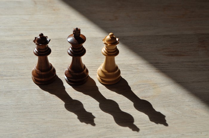 Three chess pieces with shadows on wood