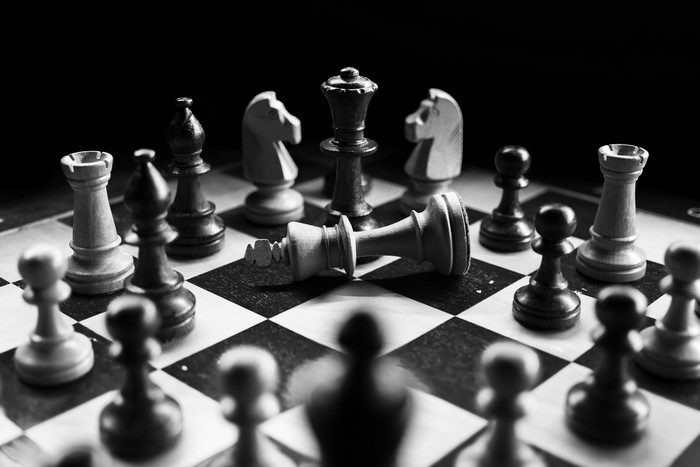 Chess game with fallen king and black and white pieces