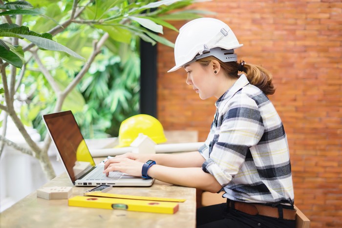 Woman in hard hat working on laptop