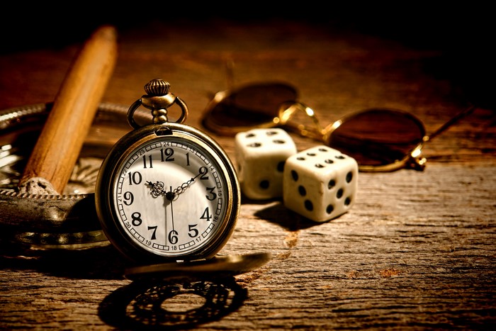 Pocket watch, dice, cigar, and sunglasses on wooden table