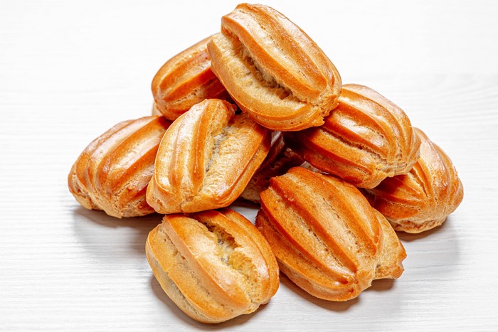 Pile of golden brown eclairs on a white surface