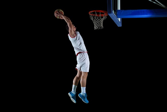 Basketball player dunking on a black background