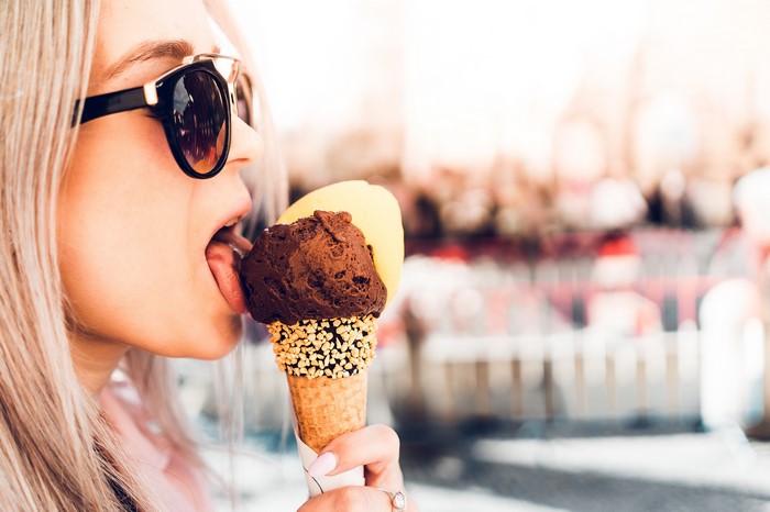 Blonde girl eating chocolate and yellow ice cream