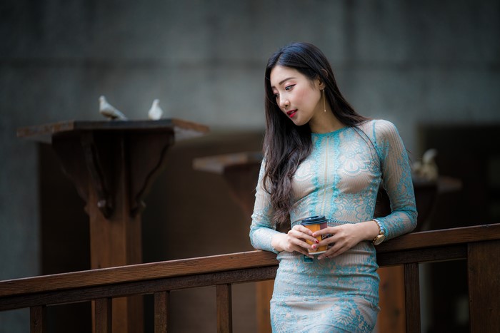 Asian woman in dress holding coffee cup