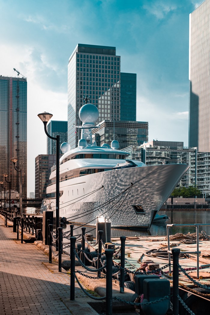 Luxury yacht docked in London with modern skyscrapers