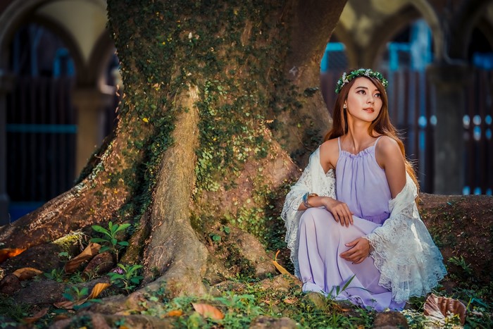 Asian woman with wreath sitting by tree