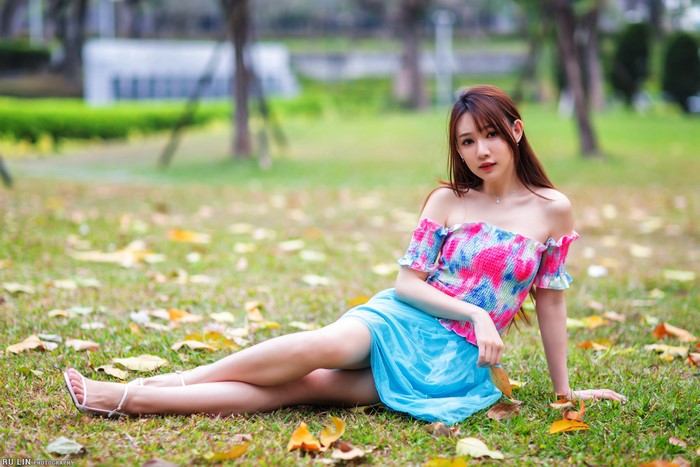 Asian woman with brown hair sitting on grass