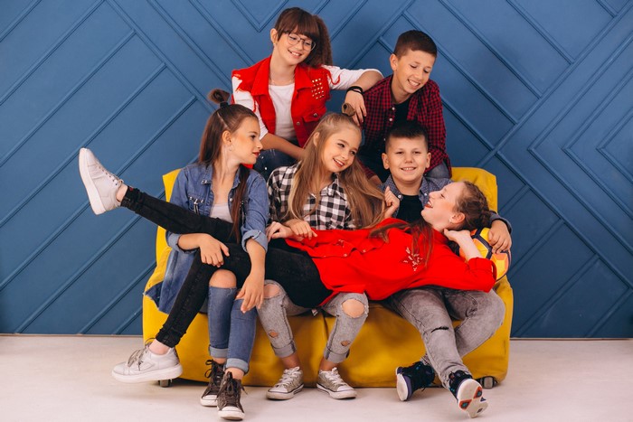 Group of happy children posing on a yellow couch