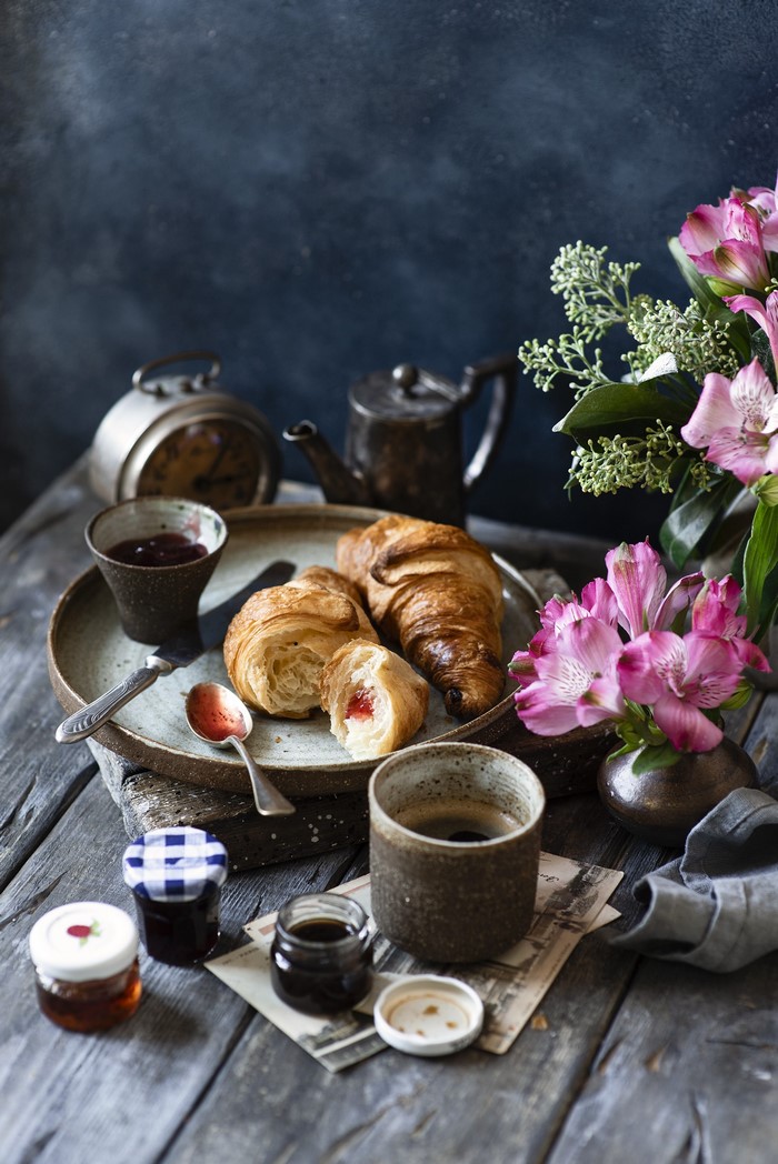 Still-life with croissants, jam, coffee, and flowers