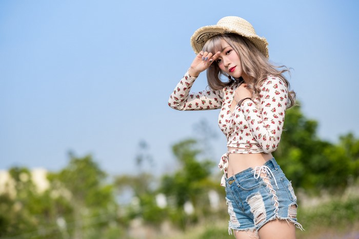 Asian woman in hat and shorts