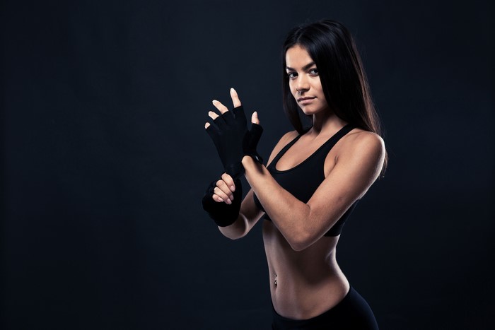 Brunette girl in fitness gear wrapping gloves