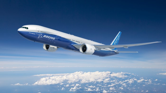 Boeing 777-300ER airplane flying above clouds