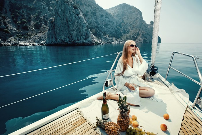 Woman in bathrobe on a yacht with fruit and champagne