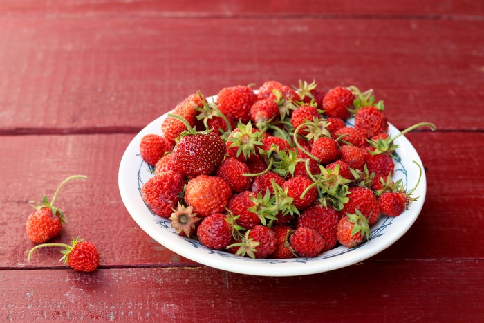 Strawberries in a plate on a red wooden table