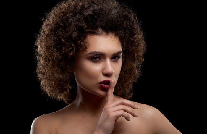Model with curly hair and makeup gesture
