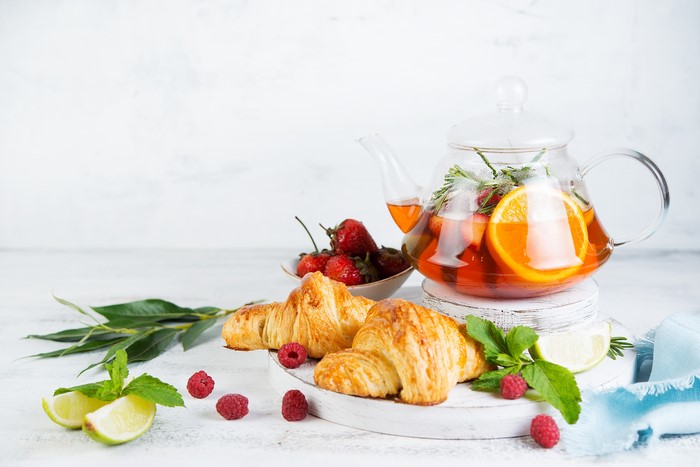 Tea with croissants, strawberries, and citrus fruits