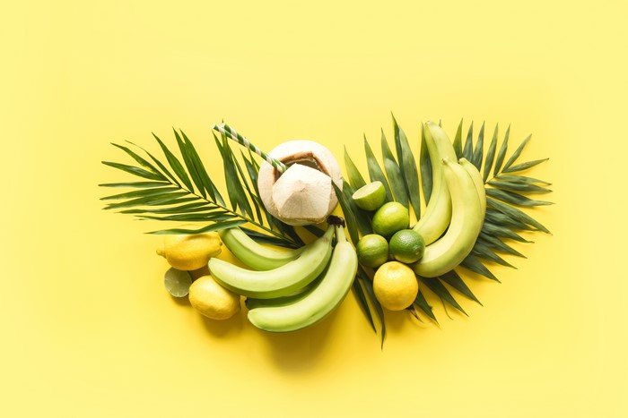 Bananas, Lemons, Coconuts, Limes, and Palm Leaves on Yellow Background