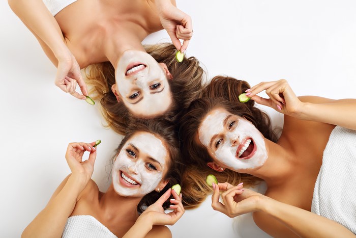 Three women with face masks and cucumbers