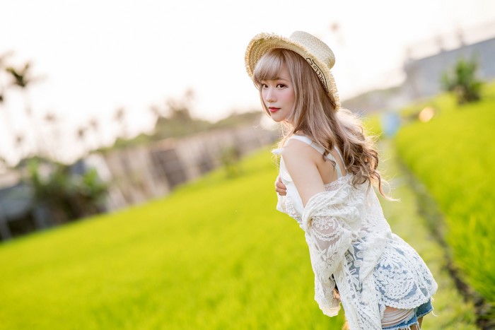 Asian woman in straw hat and white lace top
