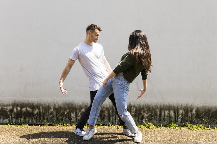 Man and woman dancing in front of a wall