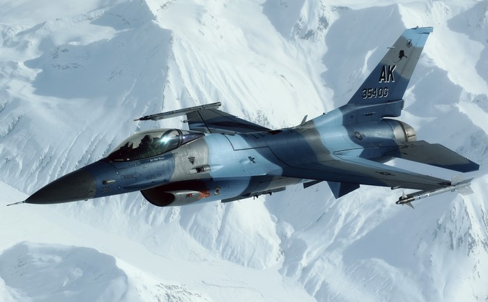 F-16 Fighting Falcon flying over snowy mountains