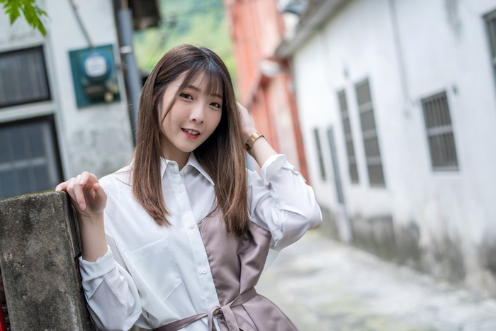 Asian woman with brown hair in a white and brown shirt