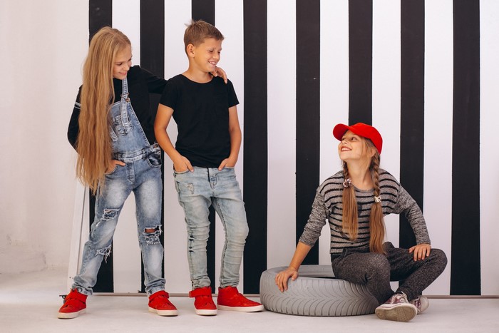 Three children posing in front of a striped background