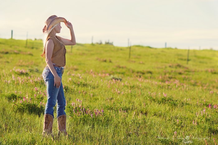 Blonde girl in cowboy hat and jeans in grasslands