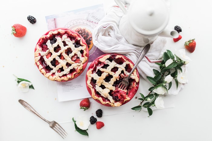 Two berry pies with a fork and teapot