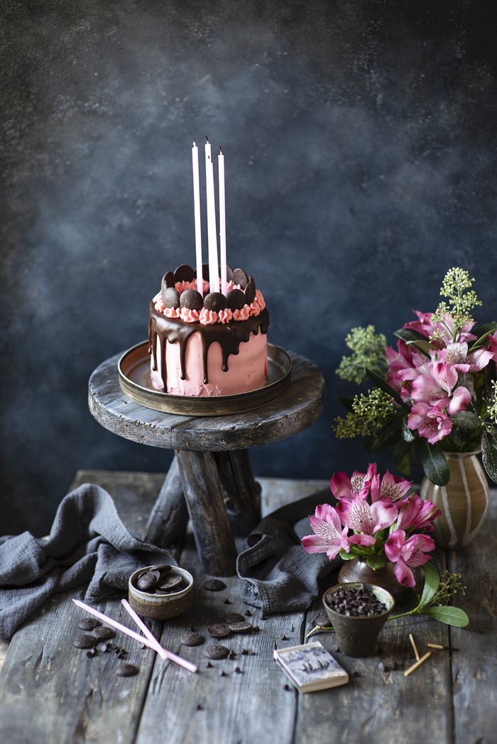 Pink chocolate drip cake with candles and flowers