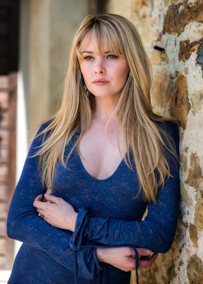 Carla Monaco leaning against a stone wall