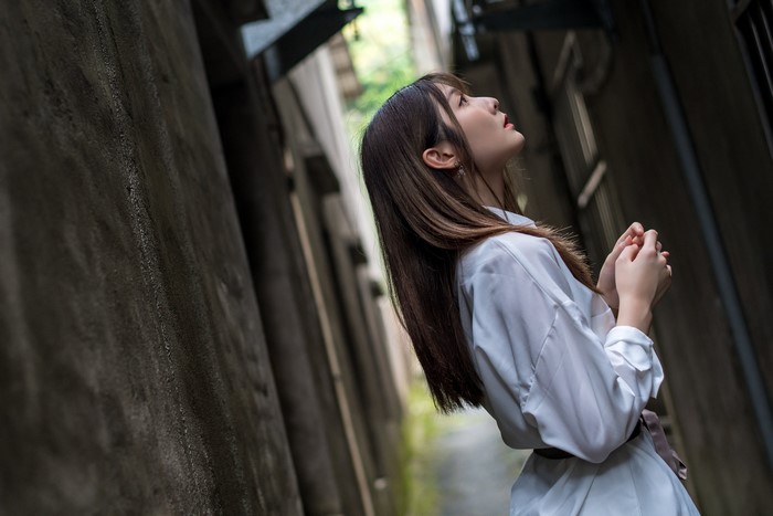 Asian woman in white dress looking up