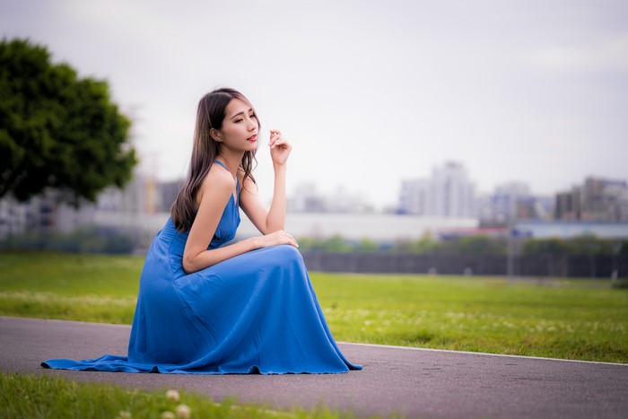 Asian woman in blue dress sitting in park