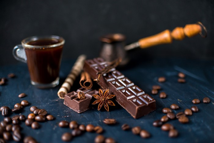 Chocolate, coffee beans, and spices on a dark surface
