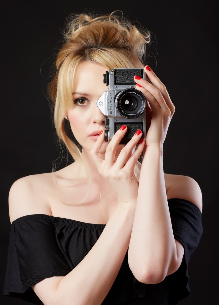 Blonde woman holding a Pentax camera