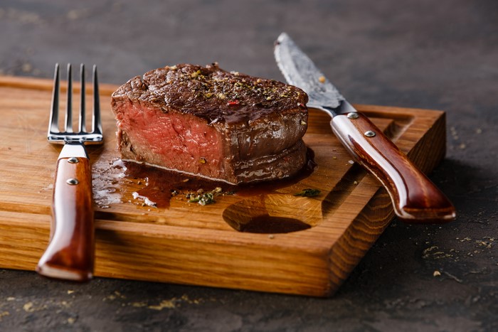 Beef steak with fork and knife on cutting board