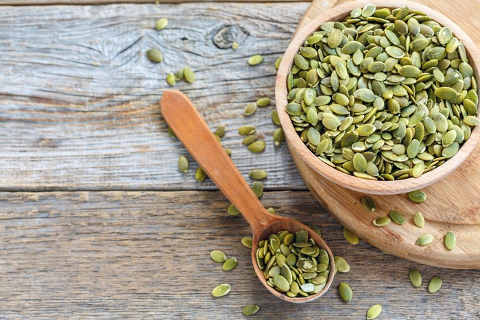 Pumpkin seeds in a bowl and spoon