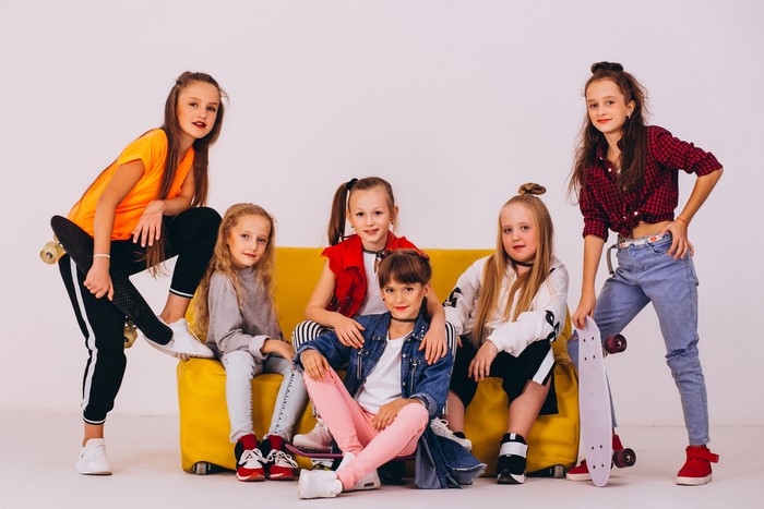 Six girls with skateboards on a yellow couch