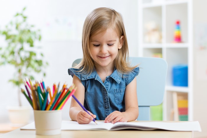 Little girl drawing with colored pencils