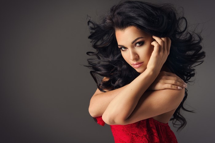 Brunette woman with dark wavy hair and red dress