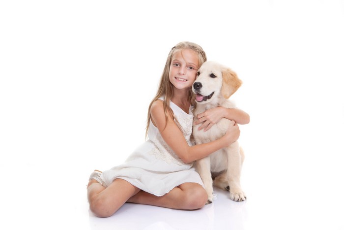 Girl hugging a Golden Retriever puppy on a white background