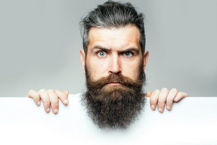 Man with beard holding a white board
