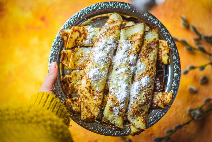 Rolled pancakes with powdered sugar on a plate