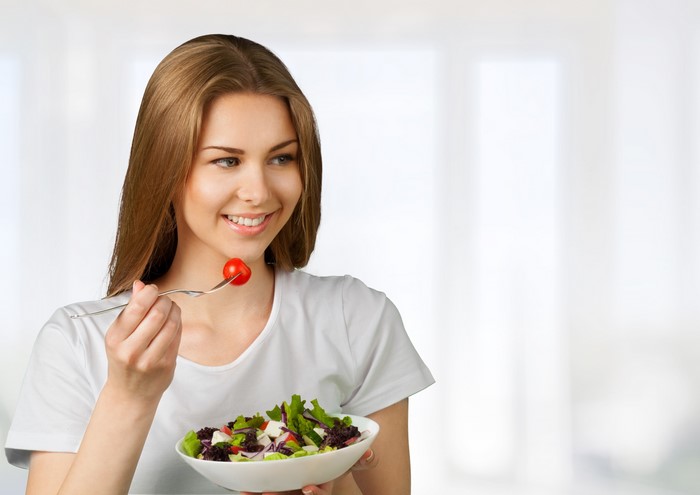 Woman Eating Salad with Cherry Tomato on Fork