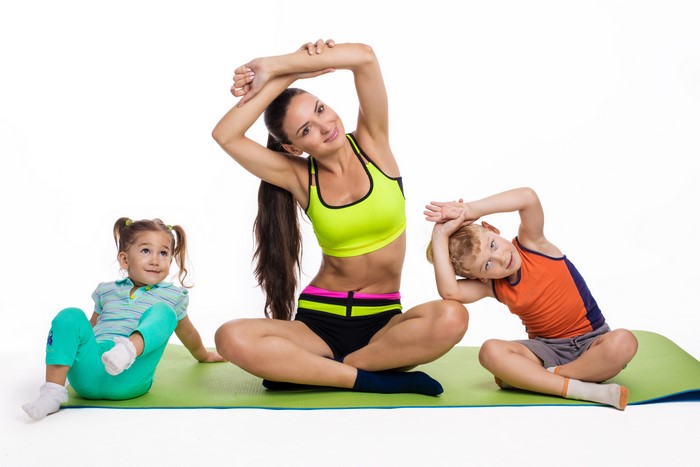 Mother and children doing yoga on a mat